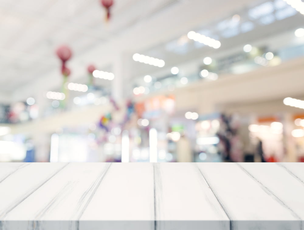 empty white table top blur shopping center background