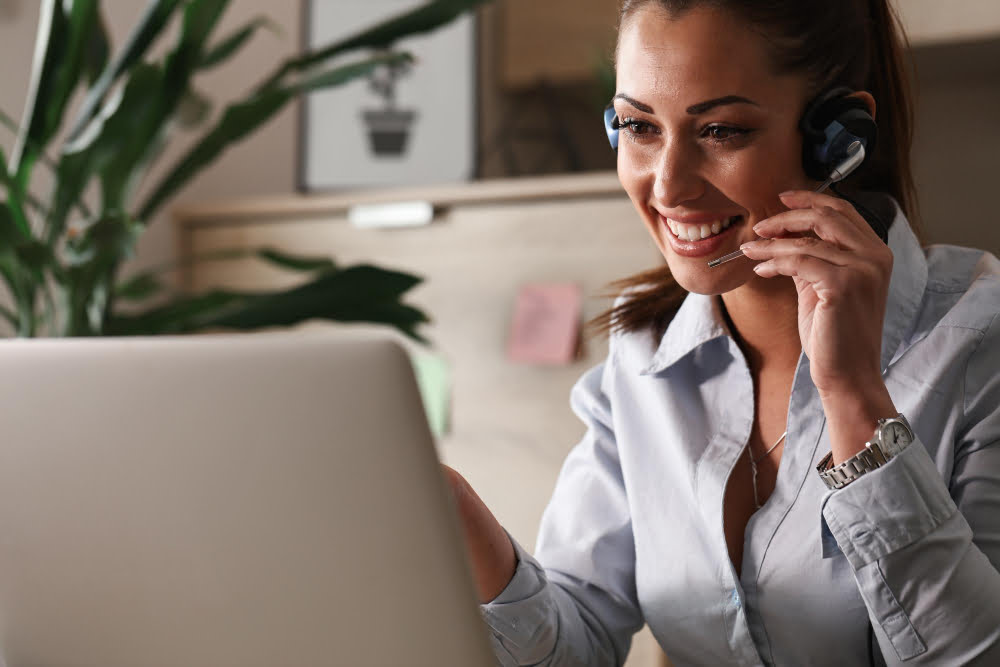 feliz representante de atendimento ao cliente conversando com um cliente enquanto usa laptop no escritorio